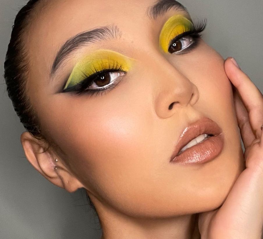 Beauty close-up with bold chartreuse yellow eyeshadow blended with black winged liner and glossy nude lip