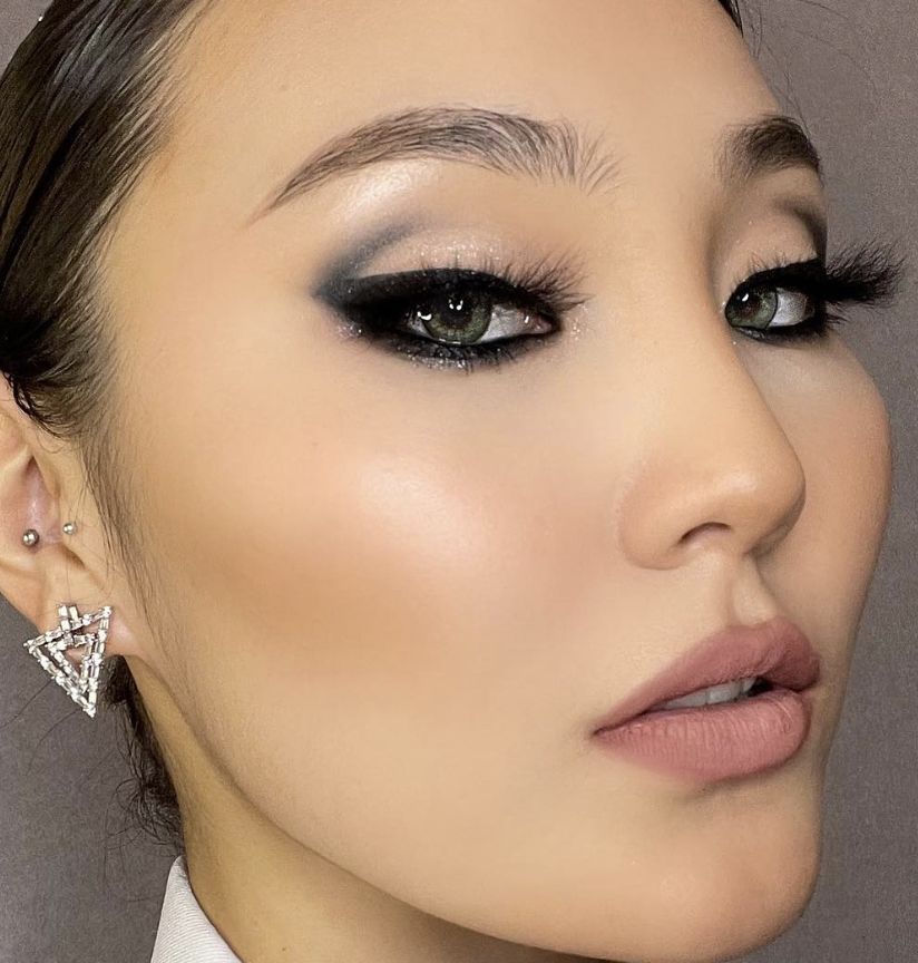 Polished smoky bronze eye makeup with shimmer, glowing skin, glossy nude lip, and a diamond-cluster earring