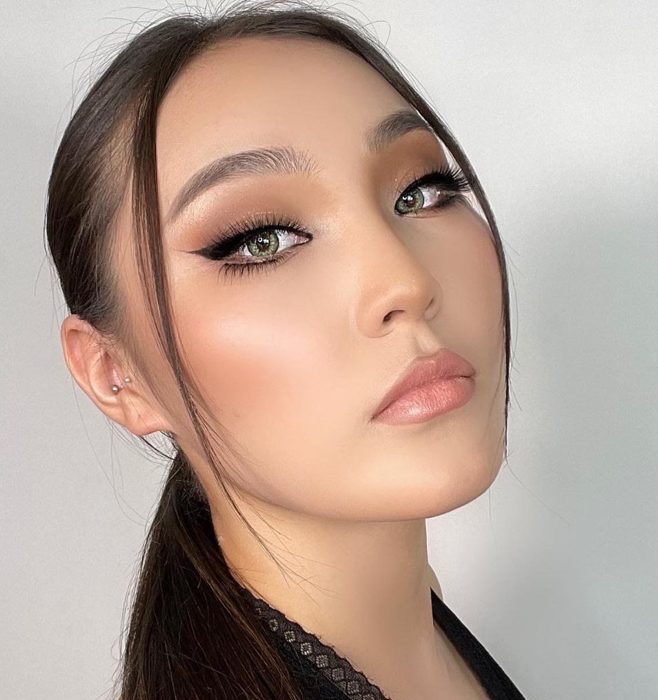 Soft brown smoky eye with winged liner, center-parted hair swept back, glowing bronzed skin and glossy nude lip