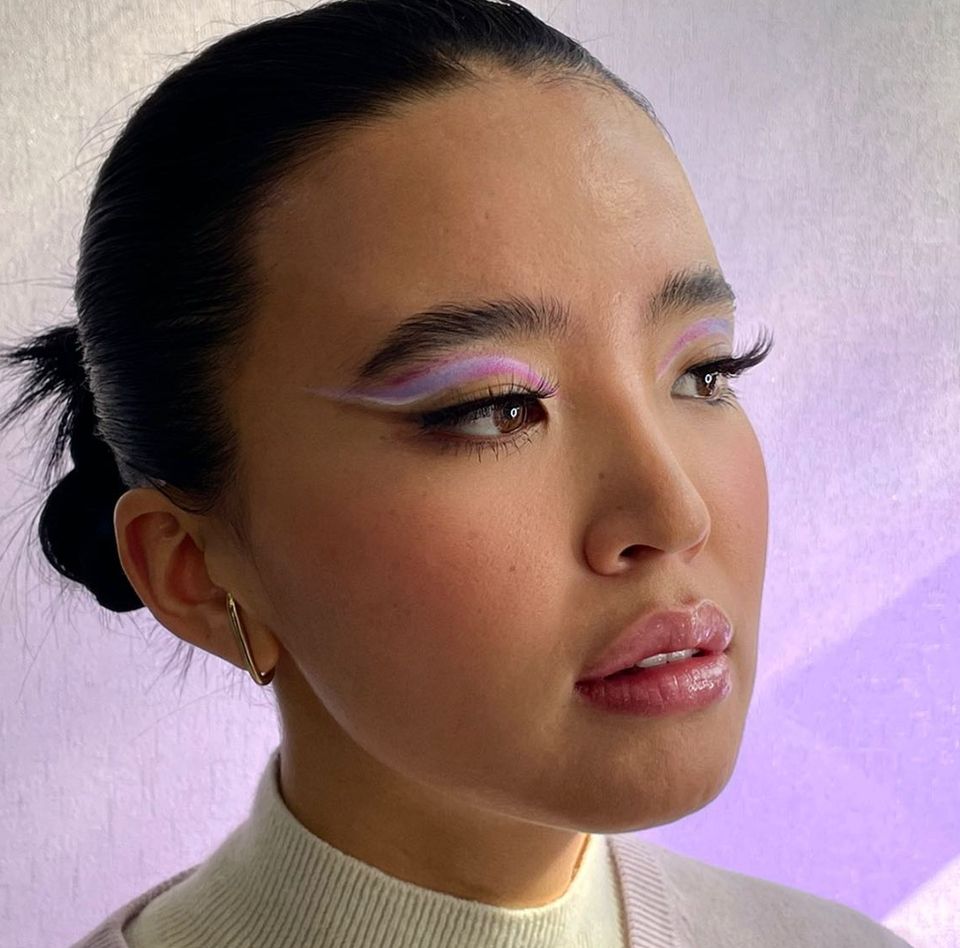 Side-profile close-up with a soft pastel lilac-lavender eyeshadow wash, winged liner, and a glossy pink lip